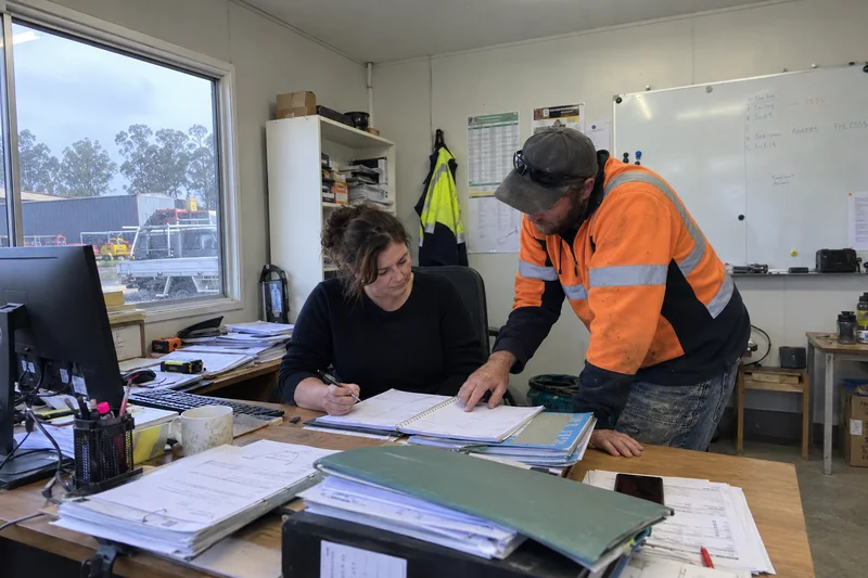An office coordinator and site supervisor reviewing the job schedule